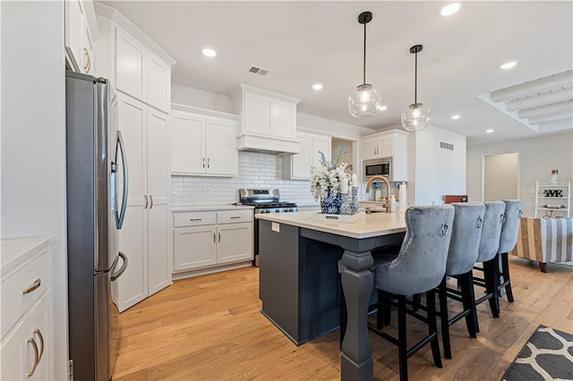 kitchen with decorative backsplash, white cabinetry, appliances with stainless steel finishes, and a breakfast bar