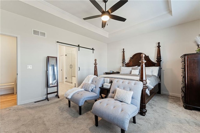 bedroom with visible vents, baseboards, a barn door, light carpet, and a raised ceiling