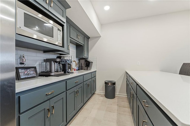 kitchen featuring a sink, tasteful backsplash, appliances with stainless steel finishes, light countertops, and light tile patterned floors