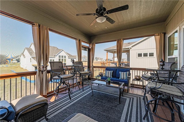 sunroom featuring wood ceiling, a residential view, and ceiling fan