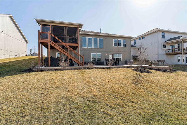 back of property featuring a lawn, stairs, a patio, and a sunroom