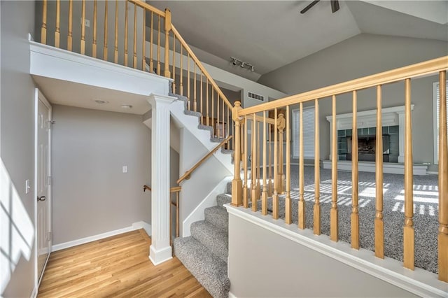 stairway with visible vents, baseboards, wood finished floors, and vaulted ceiling