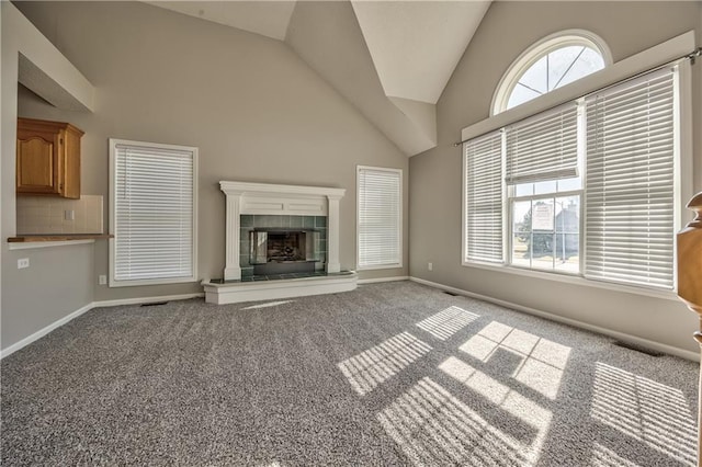 unfurnished living room featuring carpet flooring, baseboards, vaulted ceiling, and a tile fireplace