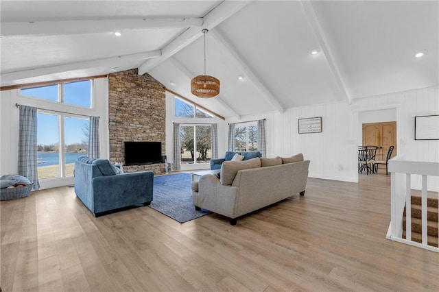 living room with light wood-type flooring, beam ceiling, high vaulted ceiling, and a fireplace