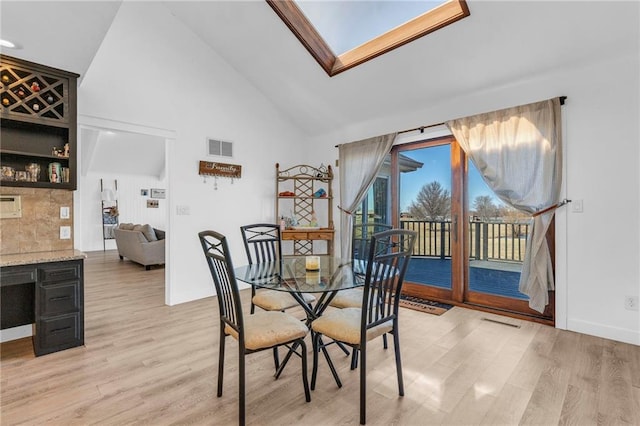 dining space with visible vents, high vaulted ceiling, and light wood-type flooring