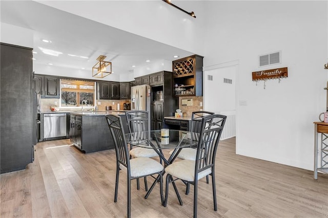 dining space with a high ceiling, light wood-style flooring, recessed lighting, and visible vents