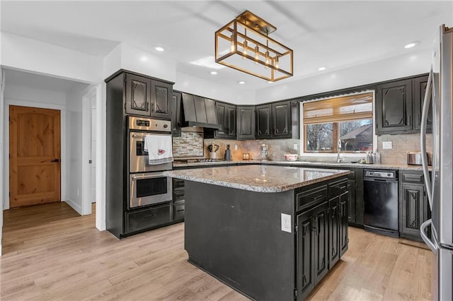 kitchen with backsplash, dark cabinetry, a center island, stainless steel appliances, and light wood-style floors