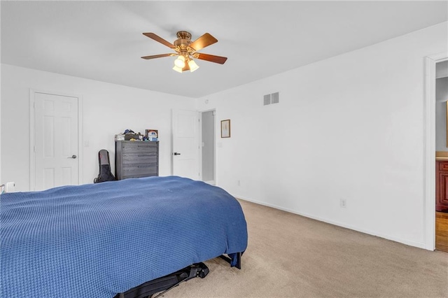 carpeted bedroom with connected bathroom, baseboards, visible vents, and ceiling fan