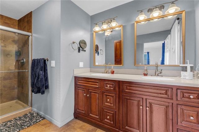 full bath with a shower stall, double vanity, baseboards, and a sink