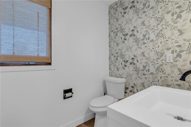 bathroom with toilet, baseboards, and a sink