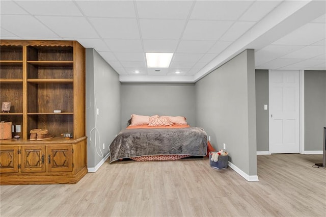 bedroom featuring a paneled ceiling, baseboards, and wood finished floors