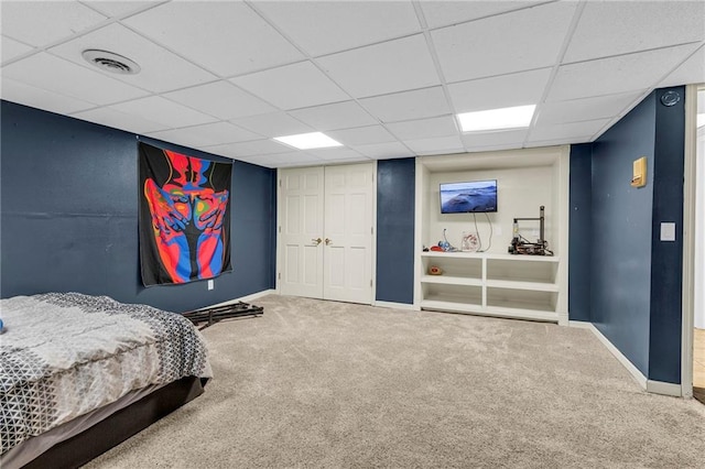 carpeted bedroom with a paneled ceiling, baseboards, and visible vents