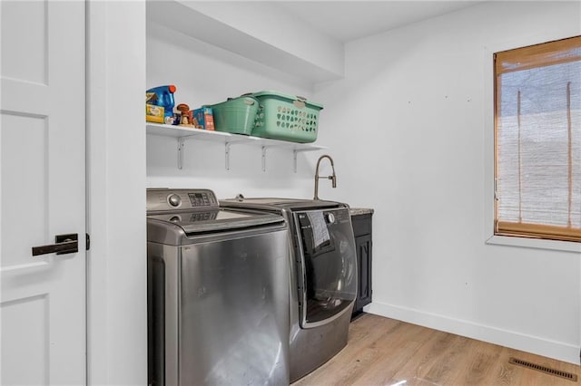 laundry area featuring visible vents, baseboards, light wood finished floors, laundry area, and washer and dryer