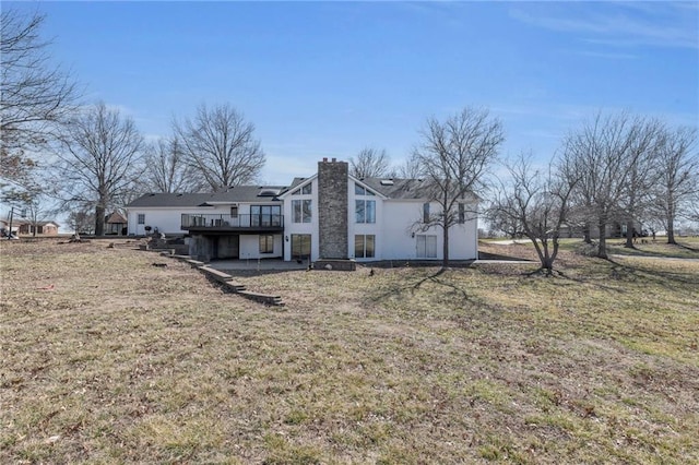 back of property with a deck, a lawn, and a chimney