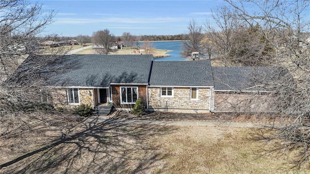 view of front of home with stone siding, a shingled roof, and a water view