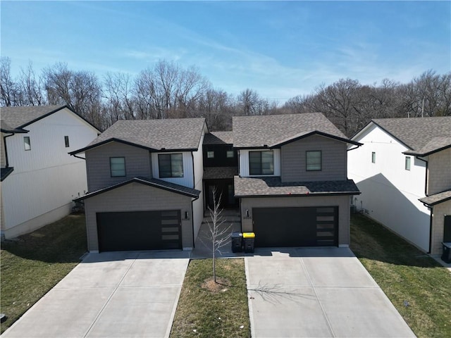 view of front facade with an attached garage, driveway, a front lawn, and roof with shingles