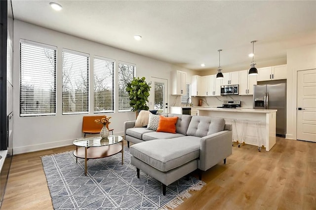 living area with recessed lighting, light wood-style flooring, and baseboards