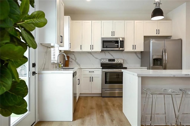 kitchen with a sink, decorative backsplash, white cabinets, and stainless steel appliances