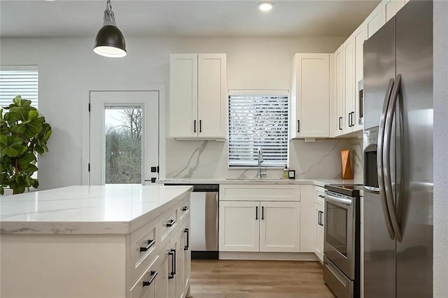 kitchen featuring white cabinets, tasteful backsplash, light wood-type flooring, and appliances with stainless steel finishes