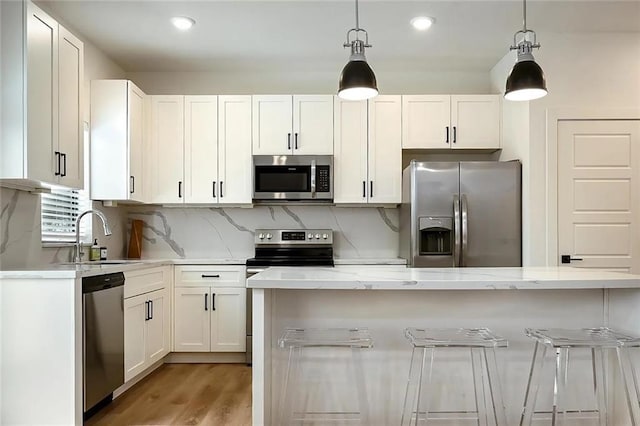 kitchen featuring decorative light fixtures, decorative backsplash, white cabinetry, and stainless steel appliances