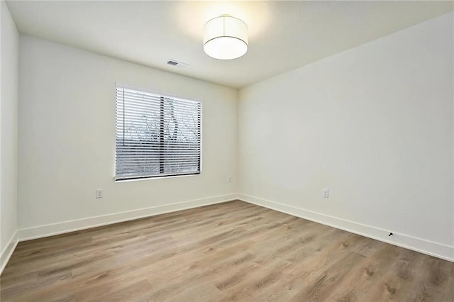 empty room featuring visible vents, baseboards, and wood finished floors