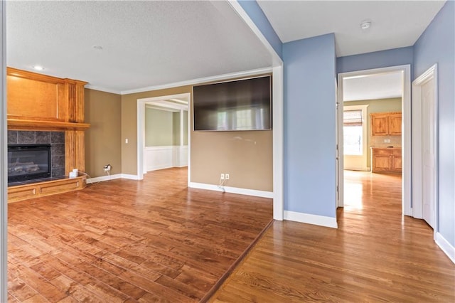 24987 W 150th Ct, Olathe, KS 66061 - unfurnished living room featuring a tile fireplace, wood finished floors, and baseboards
