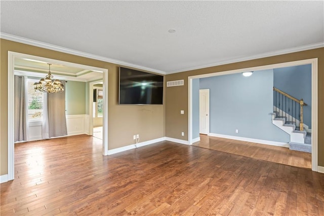 24987 W 150th Ct, Olathe, KS 66061 - unfurnished living room featuring crown molding, visible vents, wood finished floors, and an inviting chandelier