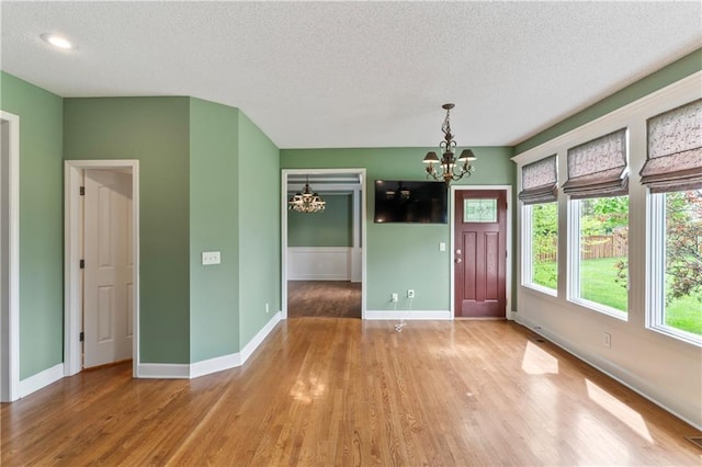 24987 W 150th Ct, Olathe, KS 66061 - unfurnished dining area with a chandelier, a textured ceiling, baseboards, and wood finished floors