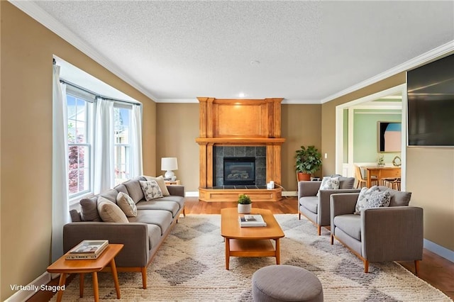 24987 W 150th Ct, Olathe, KS 66061 - living area featuring ornamental molding, baseboards, light wood finished floors, a tiled fireplace, and a textured ceiling