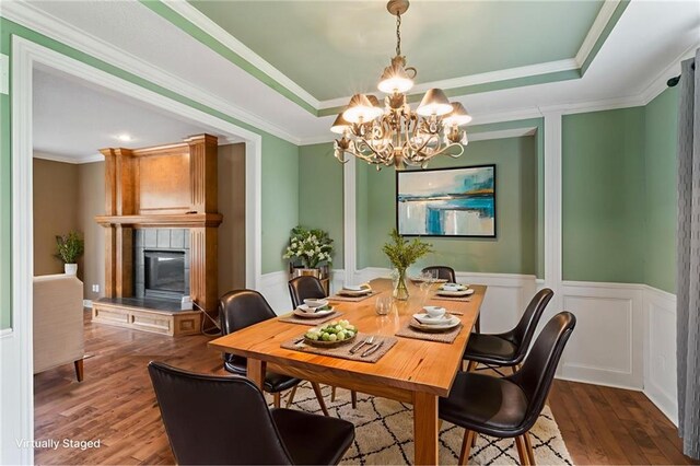 24987 W 150th Ct, Olathe, KS 66061 - dining area with a chandelier, a raised ceiling, wood finished floors, a tile fireplace, and wainscoting
