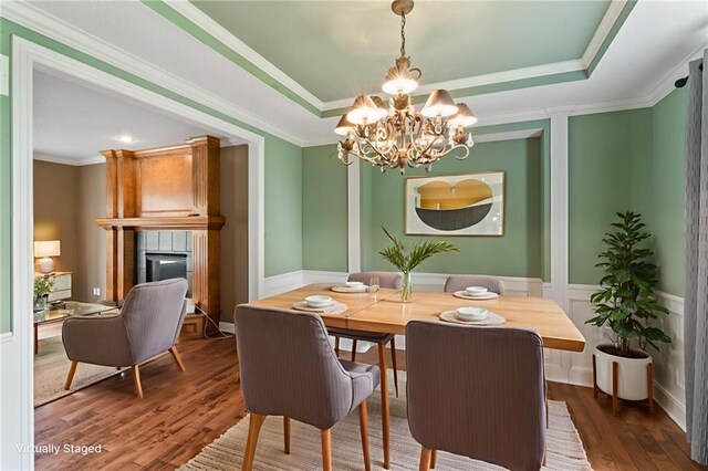 24987 W 150th Ct, Olathe, KS 66061 - dining area with dark wood-type flooring, a fireplace, a chandelier, a raised ceiling, and crown molding