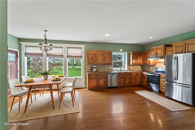 24987 W 150th Ct, Olathe, KS 66061 - kitchen featuring appliances with stainless steel finishes, a chandelier, brown cabinetry, dark wood-style flooring, and recessed lighting