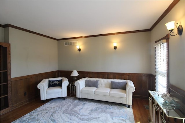 living room featuring visible vents, wood finished floors, crown molding, and a wainscoted wall