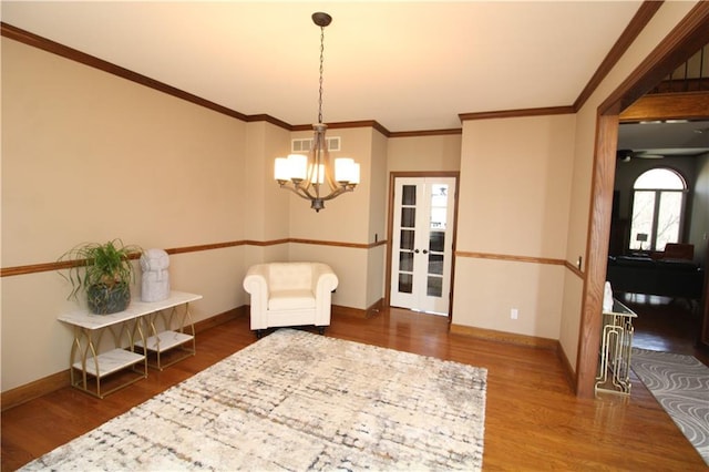 living area with crown molding, wood finished floors, and baseboards