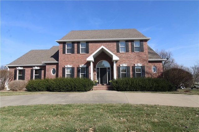 colonial house featuring brick siding and a front yard