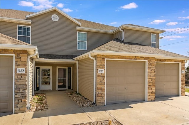 townhome / multi-family property featuring driveway, a garage, stone siding, and roof with shingles