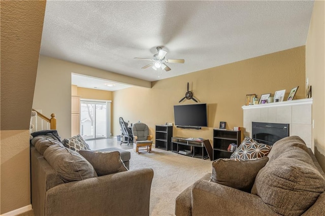 carpeted living room with a ceiling fan, a fireplace, a textured wall, and a textured ceiling