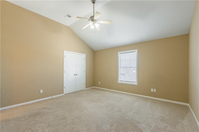 carpeted spare room with visible vents, a ceiling fan, baseboards, and high vaulted ceiling