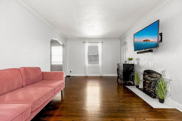 living area with baseboards, wood finished floors, ornamental molding, a textured wall, and arched walkways