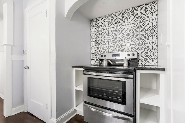 kitchen featuring baseboards, electric range, arched walkways, dark wood-style flooring, and dark countertops