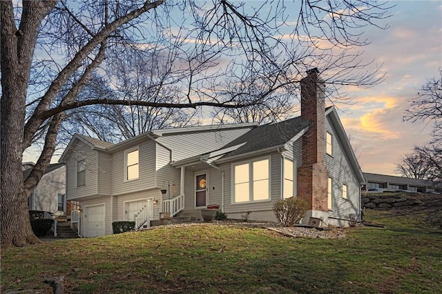 tri-level home with a garage, a front yard, and a chimney