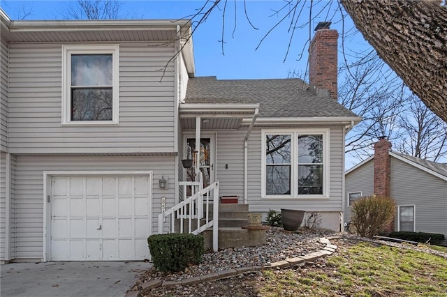 split level home featuring concrete driveway, a chimney, a garage, and a shingled roof