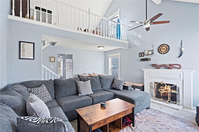 living room featuring stairway, a healthy amount of sunlight, a fireplace, and high vaulted ceiling