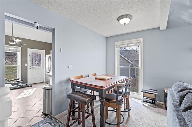 dining space with a ceiling fan, light tile patterned floors, a healthy amount of sunlight, and a textured ceiling