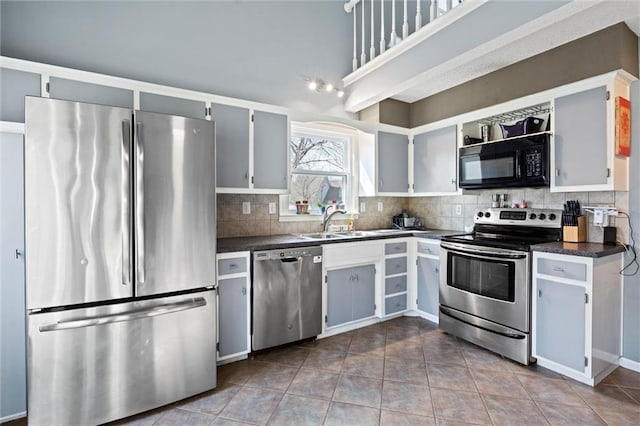 kitchen featuring dark countertops, appliances with stainless steel finishes, tasteful backsplash, and a sink