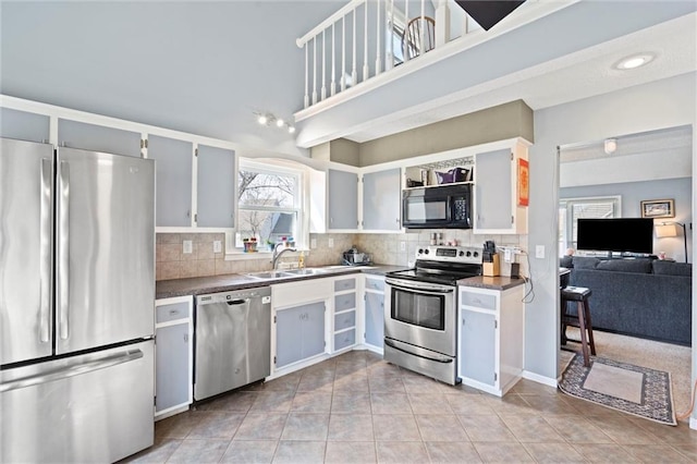 kitchen featuring a sink, stainless steel appliances, tasteful backsplash, and dark countertops