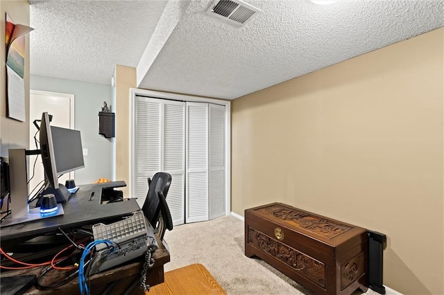 office featuring carpet flooring, baseboards, visible vents, and a textured ceiling