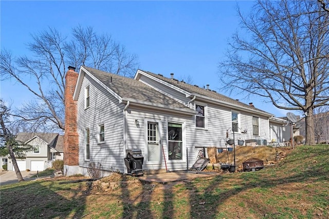 back of property featuring a chimney and a shingled roof