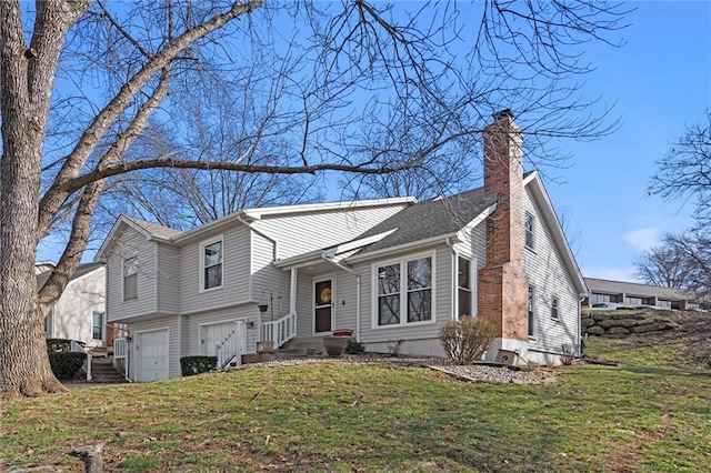 tri-level home with a front yard, an attached garage, and a chimney