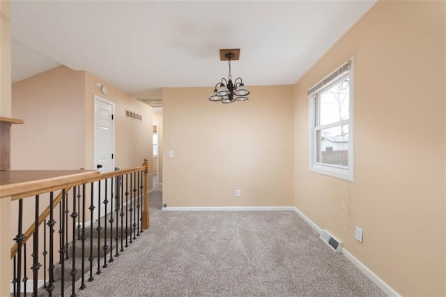 carpeted spare room with visible vents, baseboards, and a chandelier